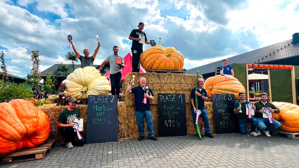 Strahlende Sieger zwischen den Kürbis-Giganten: Kevin Rataj gewann mit offiziell 689,5 Kilogramm vor dem Belgier Mark Feyaerts mit 521,5 Kilogramm. Tristan Möller belegte mit 521 Kilogramm Platz drei und wurde zugleich NRW-Meister. Gemeinsam mit ihnen freuten sich die weiteren Preisträger der Wiegemeisterschaft. Foto: Krewelshof/pp/Agentur ProfiPress
