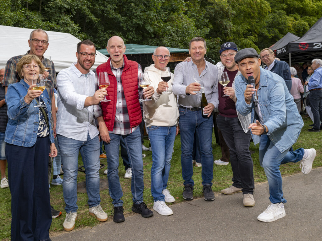 Prost Mechernich-Nyons: Die Freundeskreis-Vorstandsmitglieder Angelika Rhein (v.l.), Klaus Tiemann, Carsten Cönen, Wilfried Hamacher, Ralf Claßen, Andreas Sack und Tim Böpple-Thieme freuten sich mit Sänger Stephan Simons über die gelungene Weinfest-Premiere. Foto: Ronald Larmann/pp/Agentur ProfiPress