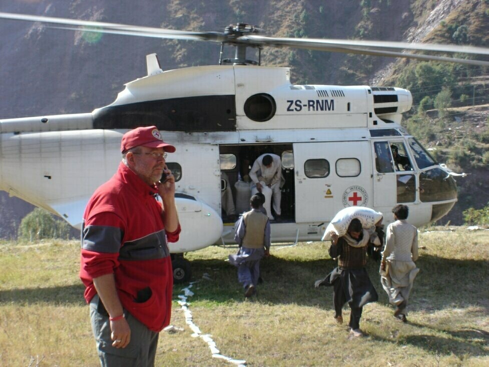 Rolf Zimmermann koordinierte nach dem verheerenden Erdbeben von 2005 Hilfsmaßnahmen des Roten Kreuzes in Pakistan. Während ein Hubschrauber des Internationalen Komitees vom Roten Kreuz Hilfsgüter in die schwer zugängliche Bergregion bringt, hält der Euskirchener Rotkreuzmann telefonisch Verbindung zu den Einsatzkräften vor Ort. Foto: Rotes Kreuz/pp/Agentur ProfiPress