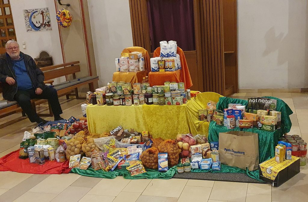 Kirchenaktivist Werner Zeyen neben einem Berg haltbarer Lebensmittel, der bei einem der früheren Sankt-Martins-Gottesdienste für die Mechernicher Tafel zusammenkam. Foto: Familienmesskreis/pp/Agentur ProfiPress