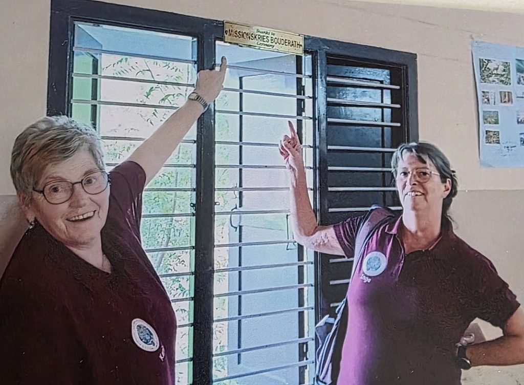 Ein kleines Schild und eine große Verbindung: Karin Raths (l.) und Ina Klinkhammer entdeckten im „Sunrise Children’s Village“ den Hinweis auf den Missionskreis St. Gertrud Bouderath – sichtbares Zeichen jahrzehntelanger Unterstützung aus der Eifel. Foto: Privat/pp/Agentur ProfiPress